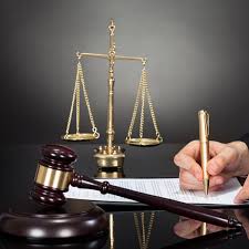 A hand holds a pen and writes legal documents